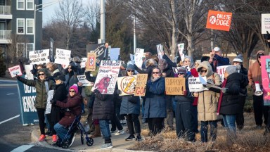 Hundreds of anti-Elon Musk protestors gather with signs and chants outside Westbury's Tesla dealership.