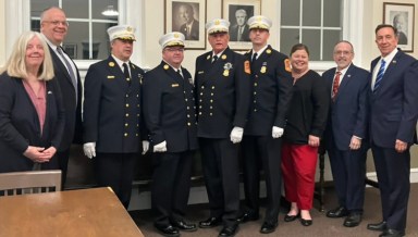 Floral Park board and fire chiefs stand next to each other in village hall.