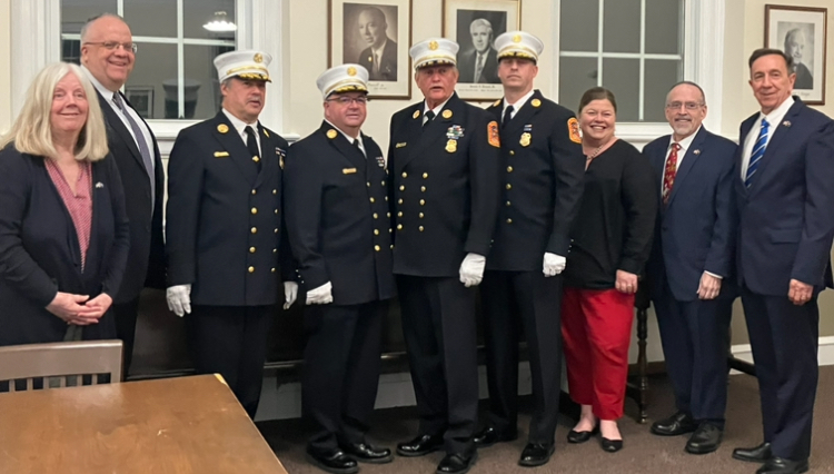 Floral Park board and fire chiefs stand next to each other in village hall.