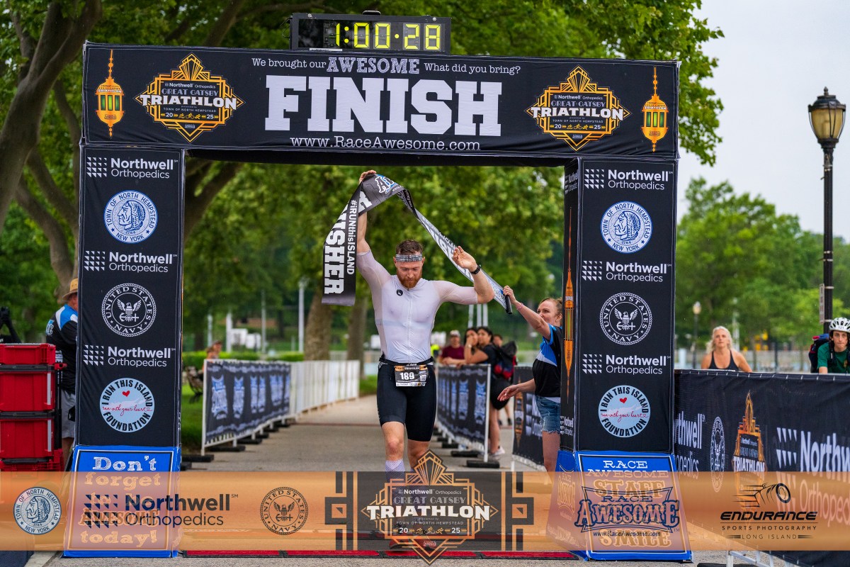 A racer crosses the finish line after completing the Great Gatsby Triathlon.