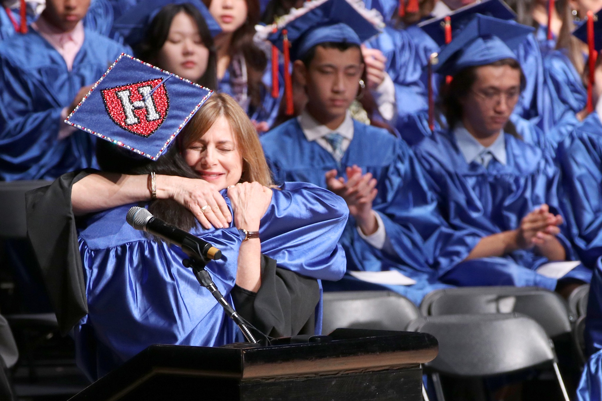 A student hugs a Great Neck South faculty member during the high school graduation ceremony.