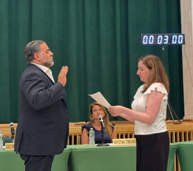 Locust Valley Board of Education President George Vasiliou (L.) was administered the oath of office by District Clerk Alison Dunne (R.)