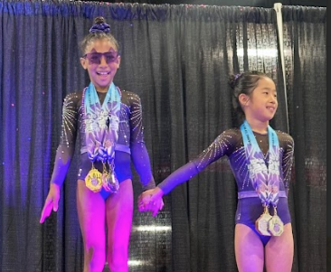 Caila Smith (L.) took the first place spot on the podium at a gymnastics competition where she qualified for the Junior Olympics.