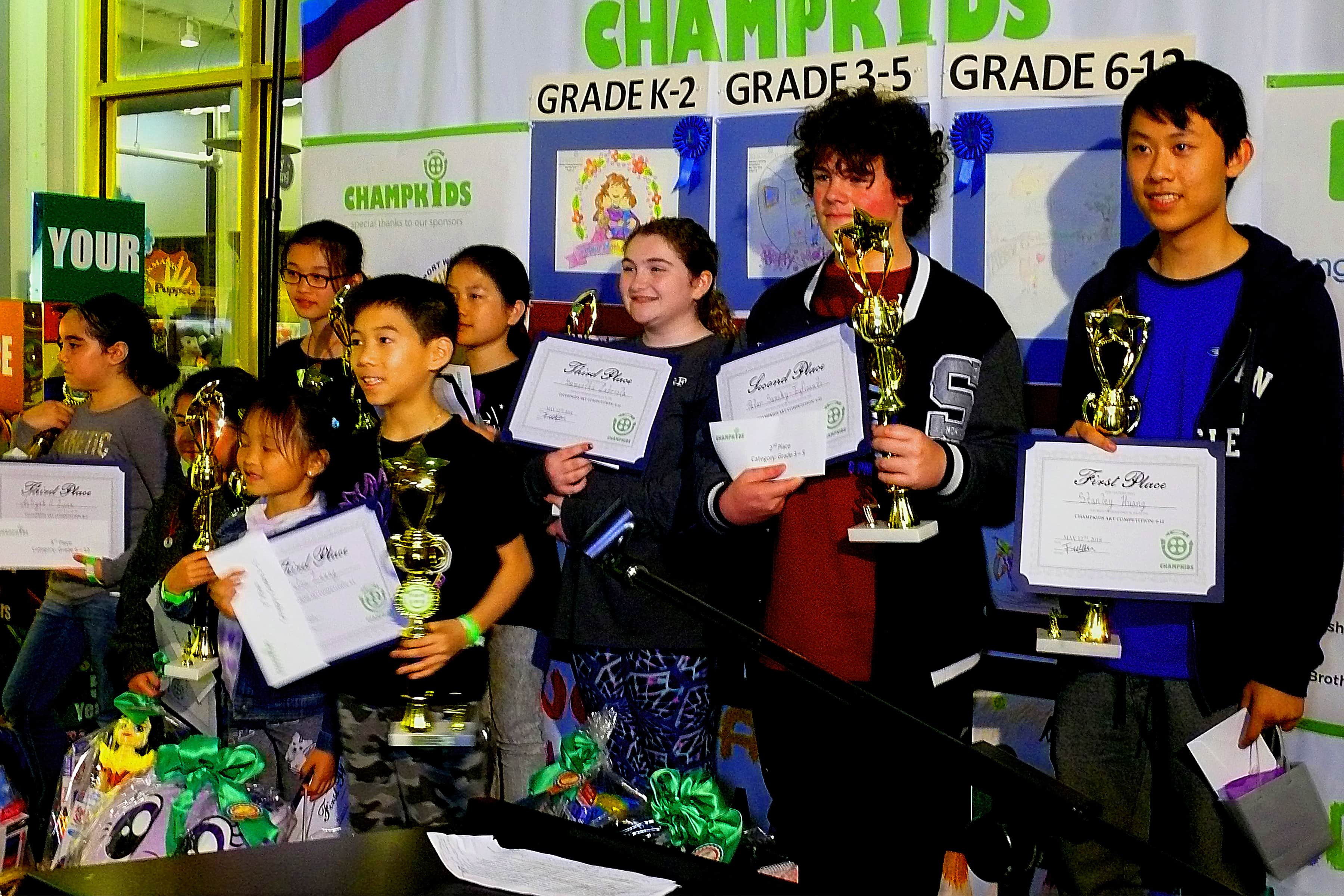 Winners of the three age groups in competition come on stage for all participants to photograpg them and to offer applause for their successful art efforts at the Saturday night program